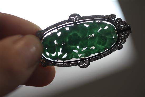 A 1920s/1930s Art Deco white gold?, pierced carved jadeite, diamond and black onyx set oval brooch, 53mm.